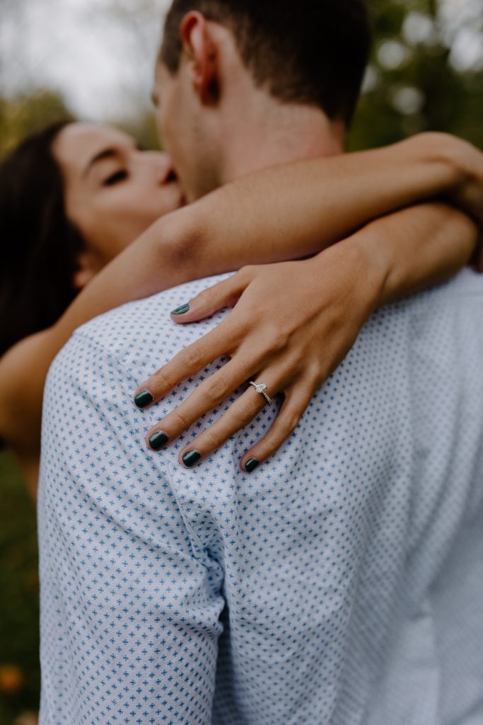 close up of man and woman kissing and showing engagement ring