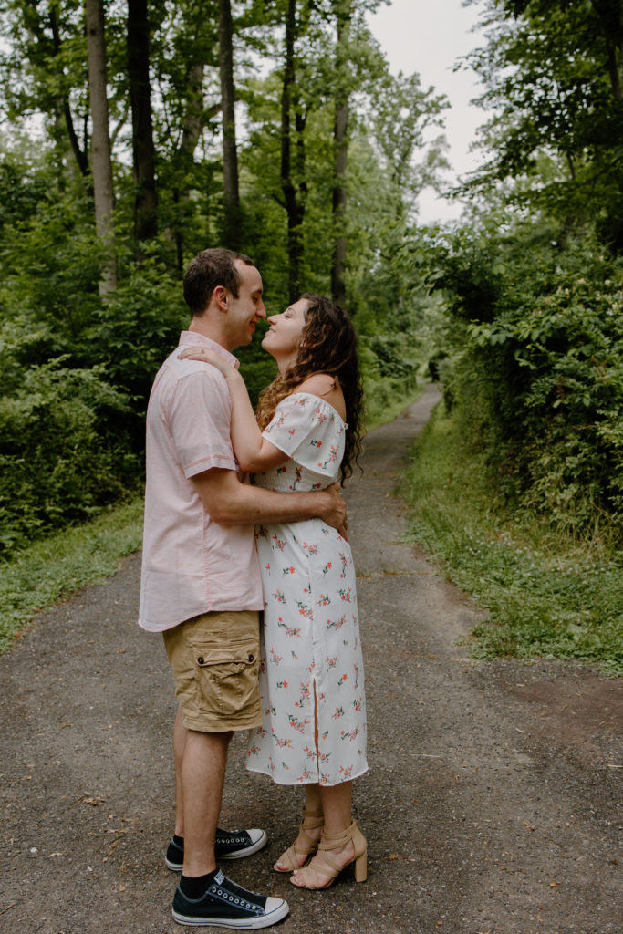 Couple standing in forest on trail looking at each other almost kissing