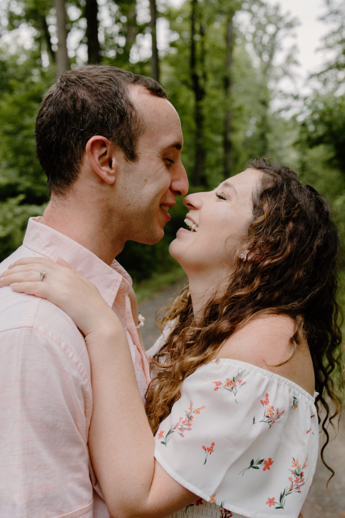 Couple standing in forest on trail looking at each other almost kissing